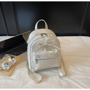 Detail of cream backpack with bow decoration and pearl pendant in a study setting