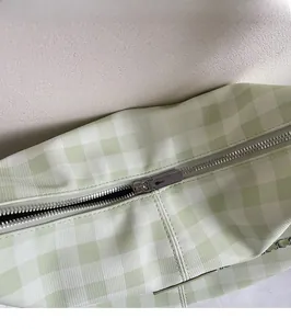 Close-up of smooth silver-tone metal zipper and plaid fabric texture on a tote bag