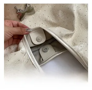 Détails des ferrures papillon argentées et du fermoir magnétique sur le sac fourre-tout