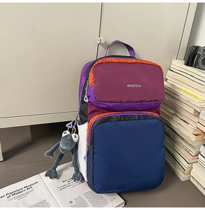 Detail of color-block backpack with multi-pockets, side mesh pouch, and plush frog charm