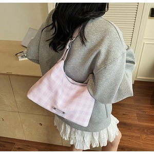 Détail du sac hobo à carreaux roses avec logo en métal et bandoulière réglable sur modèle
