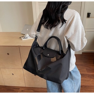 Detail of a black nylon travel tote with leather handles and detachable shoulder strap