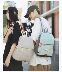 Close-up of compact nylon backpack with decorative orange elastic ropes for outdoor travel