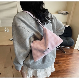 Détail du sac hobo à carreaux violet clair porté à l'épaule par un mannequin en intérieur