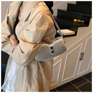 Macro detail of a metallic silver shoulder bag with buckle and khaki trench coat outfit