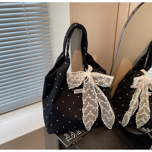 Détail d'un sac cabas en toile fleurie avec nœud en dentelle blanche et motif floral