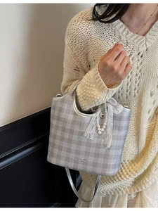 Plaid tote bag with pearl pendant shown as a crossbody on a stylish model