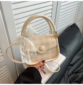 Close-up of beige gingham crossbody bag with delicate lace bow and handle detail