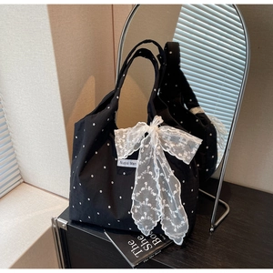 Vue détaillée du sac en toile fleurie avec nœud en dentelle blanche et étiquette