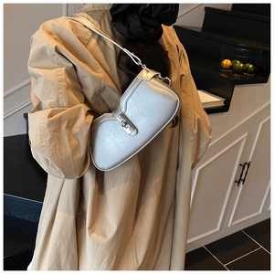 Silver metallic baguette bag shown on shoulder against a minimalist home background