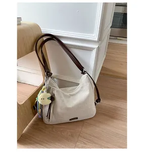 Detail of canvas tote bag with brown leather straps and cute plush pendant accessory