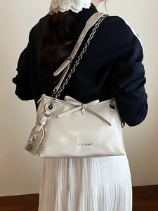 Borsa tote beige con fiocco e tracolla a catena argento indossata dalla modella