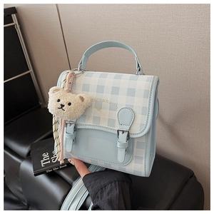 Détail du mini sac à dos à carreaux bleu clair avec breloque ours et broderies