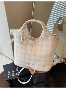 Plaid tote bag with pearl bow charm and crossbody strap in elegant lifestyle setting