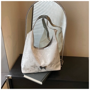 Détail d'un sac porté épaule blanc avec motifs papillons et boucle métallique argentée