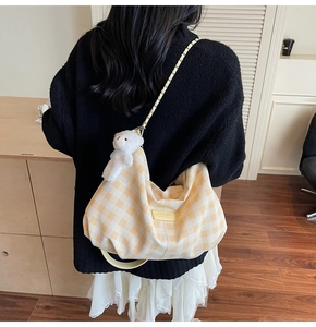 Detail of yellow checkered crossbody bag with chain strap and plush bear charm