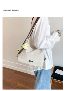 Detail of canvas tote bag with brown leather strap and cute plush chicken keychain