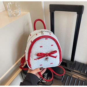 Close-up of white mini backpack with red bow prints and metallic pendant detail