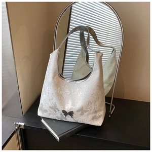 Détail d'un sac à bandoulière blanc avec imprimés papillons gris et ornement en métal