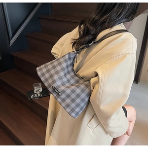 Détail du sac hobo à carreaux gris et blanc avec logo SHI SHANG et bandoulière noire