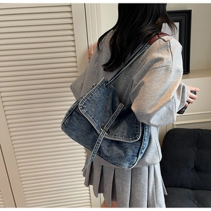 Classic denim shoulder bag in vintage blue styled with a casual outfit and metal buckles