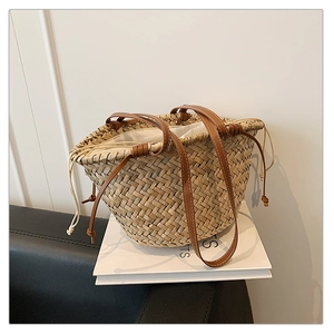 Détail du sac seau en paille tissée avec poignées en cuir marron et doublure à cordon