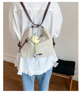 Detail of off-white canvas tote bag with brown leather straps and yellow duck charm