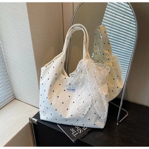 Détail du sac cabas crème avec grand nœud en dentelle et motif étoilé sur la toile
