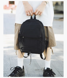 Close-up of black nylon backpack with elastic drawstrings and front zipper pocket