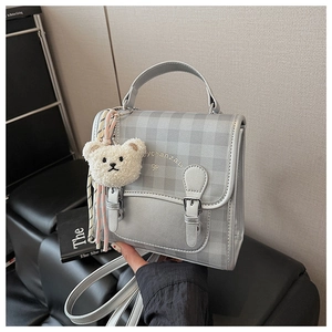 Détail d'un mini sac à dos à carreaux avec broderie et un joli charme d'ours en peluche