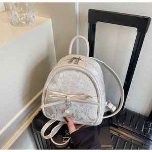 Detail of cream jacquard mini backpack with butterfly pattern and pearl bow accent