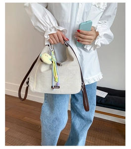 Close-up of beige canvas Hobo bag with ONJIN leather label and moon doll accessory