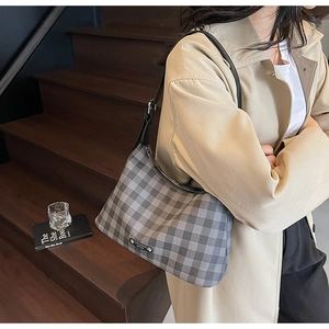 Détail du sac hobo à carreaux gris avec bandoulière en cuir dans un style de rue moderne
