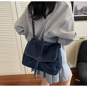 Sac à bandoulière en jean bleu avec boucle ronde en métal dans une tenue décontractée