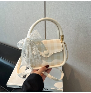 Detail of cream checkered mini handbag with white lace bow and round handle
