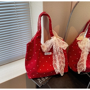 Gros plan d'un sac cabas rouge à fleurs avec grand nœud en dentelle et étiquette de marque