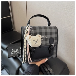 Détail du mini sac à dos à carreaux rétro avec breloque ours et sangle tissée colorée
