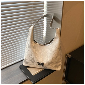 Détail du sac à bandoulière blanc avec imprimés papillons et boucle en métal noir