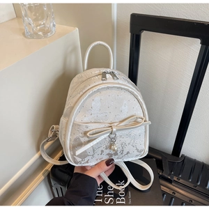 Close-up of ivory bow backpack with butterfly jacquard pattern and pearl pendant charm