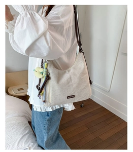 Chic cream canvas shoulder bag with brown leather strap and cute plush charm detail