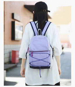 Rear view of a purple lightweight hiking backpack worn by a person in a city street setting