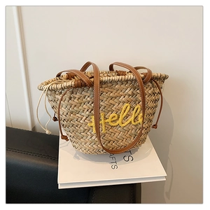 Détail d'un sac de plage en paille avec broderie Hello jaune et anses en cuir