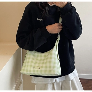 Détail du sac hobo à carreaux vert clair avec bandoulière ajustable porté par un mannequin
