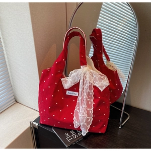 Détail du sac cabas en toile à fleurs rouges avec un grand nœud en dentelle blanche élégant
