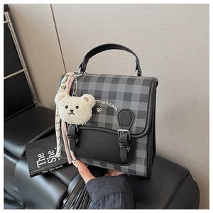 Détail du mini sac à dos à carreaux avec sangles en cuir et pendentif ours peluche