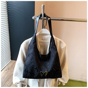 Détail du sac noir avec boucle papillon dorée et motifs à pois blancs élégants