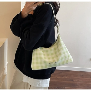 Gros plan du sac à carreaux vert et blanc avec une plaque logo métallique sophistiquée