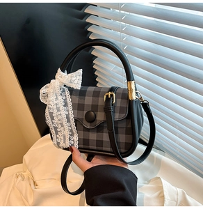 Detailed shot of a plaid handbag with white lace bow and gold metallic hardware accents