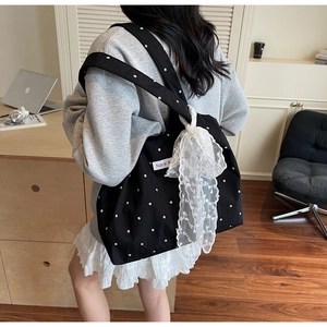 Grand sac cabas floral en toile avec nœud en dentelle porté à l'épaule dans un studio