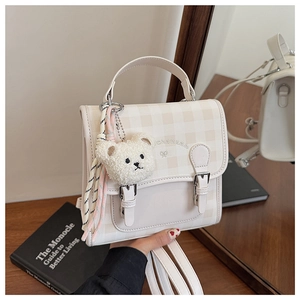 Détail du mini sac à dos à carreaux avec breloque ours en peluche et boucles décoratives